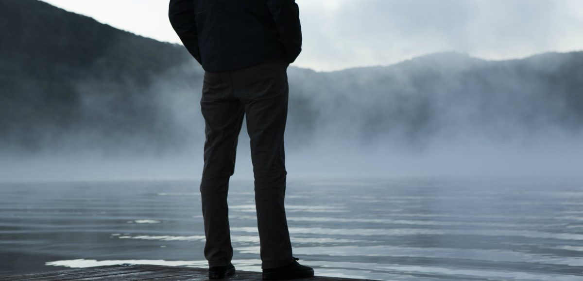 A man overlooks a lake where mist is rising